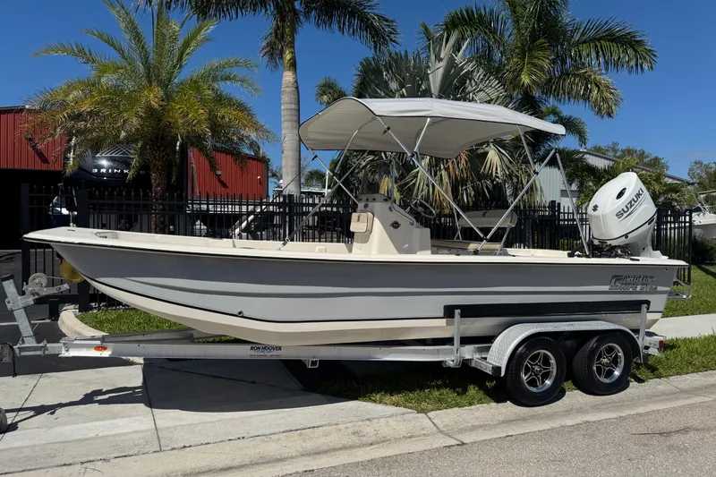 Slide: The Image of 2023 Carolina Skiff 21 SWS boat on trailer, parked near palm trees. - 77