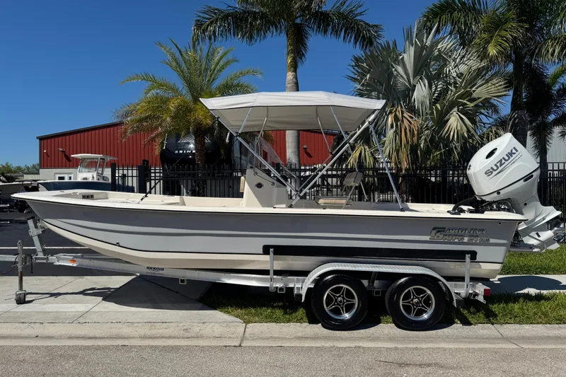 Slide: The Image of 2023 Carolina Skiff 21 SWS boat on trailer, parked near palm trees. - 78