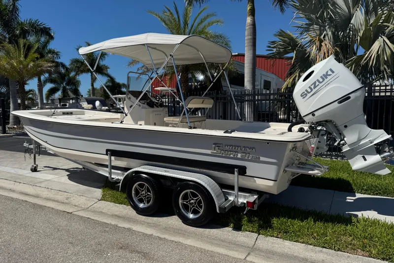 Slide: The Image of 2023 Carolina Skiff 21 SWS boat with Suzuki outboard motor on trailer, parked near palm trees. - 79