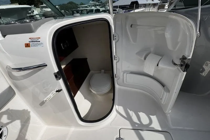 Slide: The Image of 2021 Robalo R227 Dual Console boat interior with compact marine toilet. - 14
