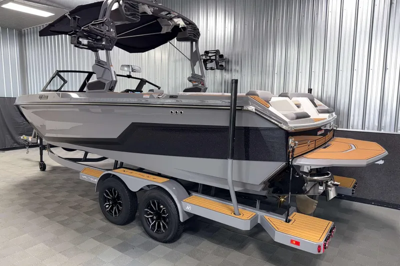 Slide: The Image of 2026 Nautique Super Air Nautique GS22 boat in showroom, sleek design, dual-axle trailer. - 38