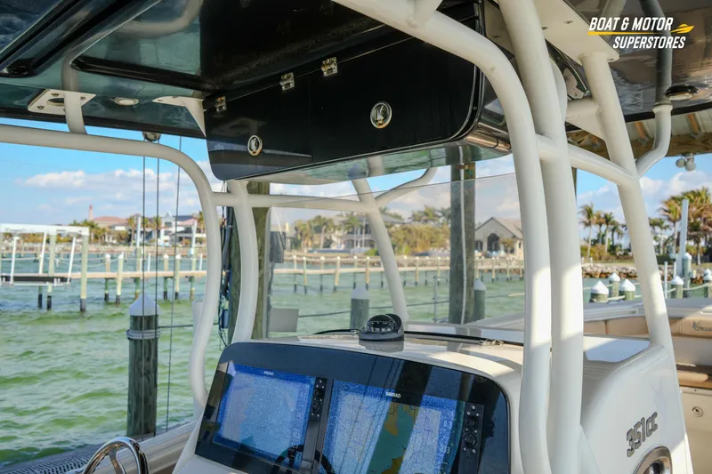 Slide: The Image of 2018 Key West Billistic 351 Center Console boat with navigation screens, docked by a scenic marina. - 104