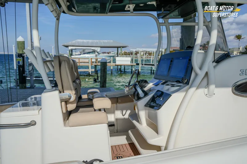 Slide: The Image of 2018 Key West Billistic 351 Center Console boat interior at dockside, featuring helm and seating. - 59