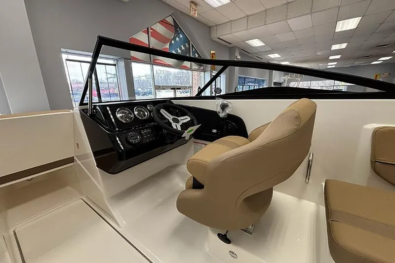 Slide: The Image of 2026 Bayliner V20 boat interior with steering wheel and beige seating in showroom. - 12