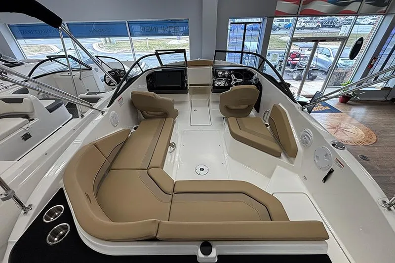 Slide: The Image of 2026 Bayliner V20 boat interior with tan seating and modern dashboard in showroom. - 6