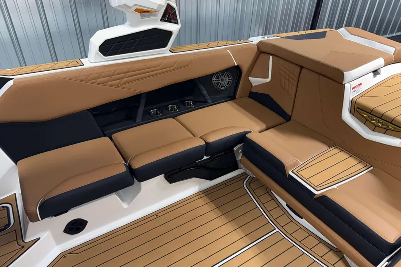 Slide: The Image of 2026 Nautique Super Air Nautique S23 interior with tan and black seating, cup holders, and speaker. - 11