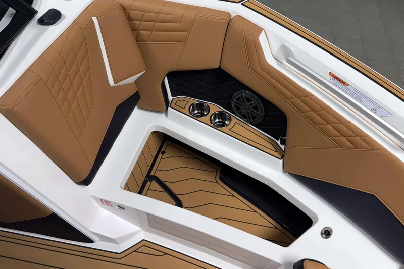 Slide: The Image of 2026 Nautique Super Air Nautique S23 interior with tan upholstery and cup holders. - 31