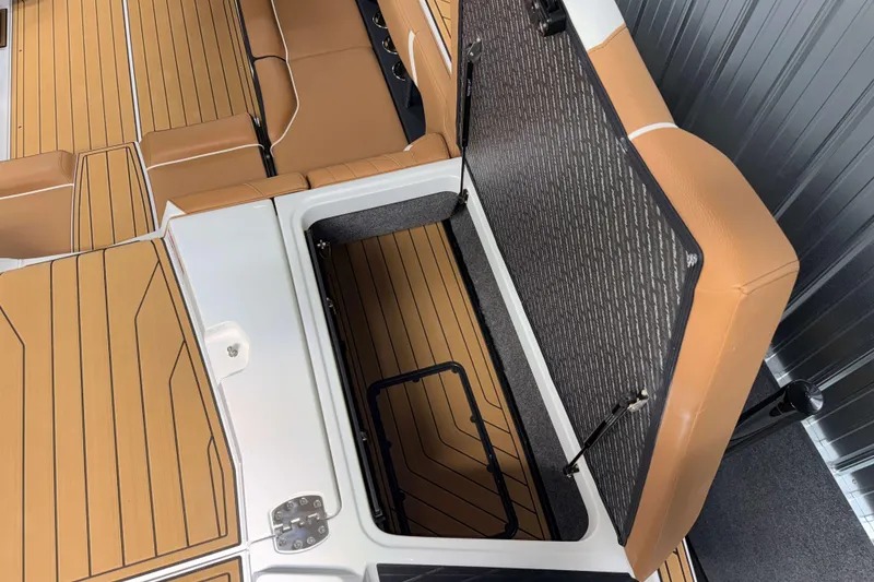 Slide: The Image of 2026 Nautique Super Air Nautique S23 interior with open storage compartment and tan seating. - 32
