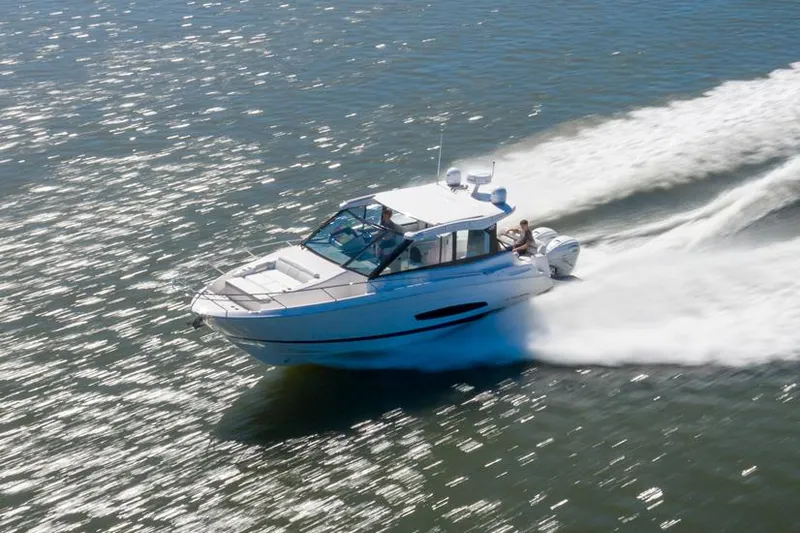 The Image of 2021 Regal 36 XO boat docked by a wooden deck with outdoor furniture. - 0