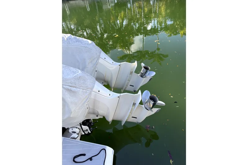 Slide: The Image of Twin outboard motors on a 2021 Regal 36 XO boat, reflected in calm water. - 35