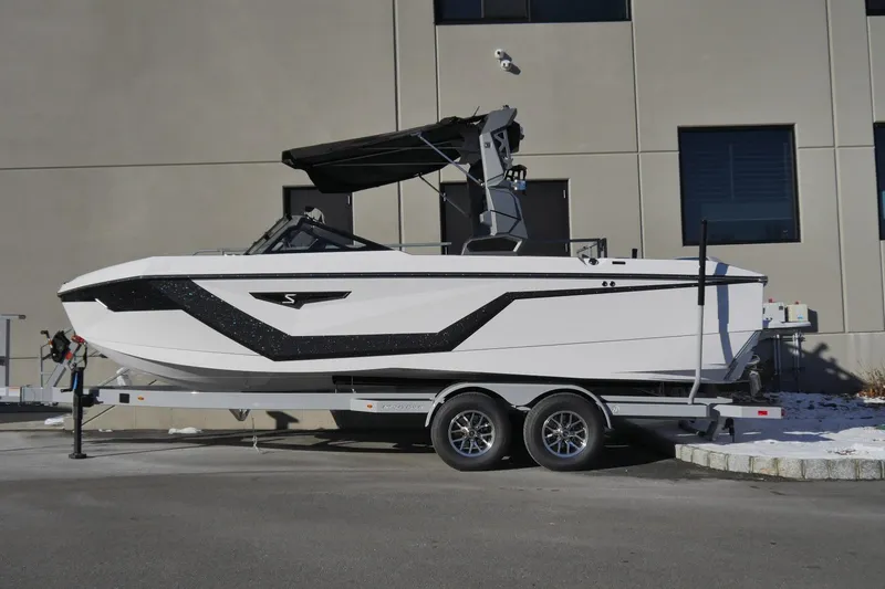 The Image of 2026 Nautique Super Air Nautique S23 boat on trailer, sleek design, parked outdoors. - 1