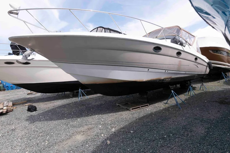 Slide: The Image of 2007 Larson Cabrio 370 boat on stands, displayed outdoors on gravel. - 2