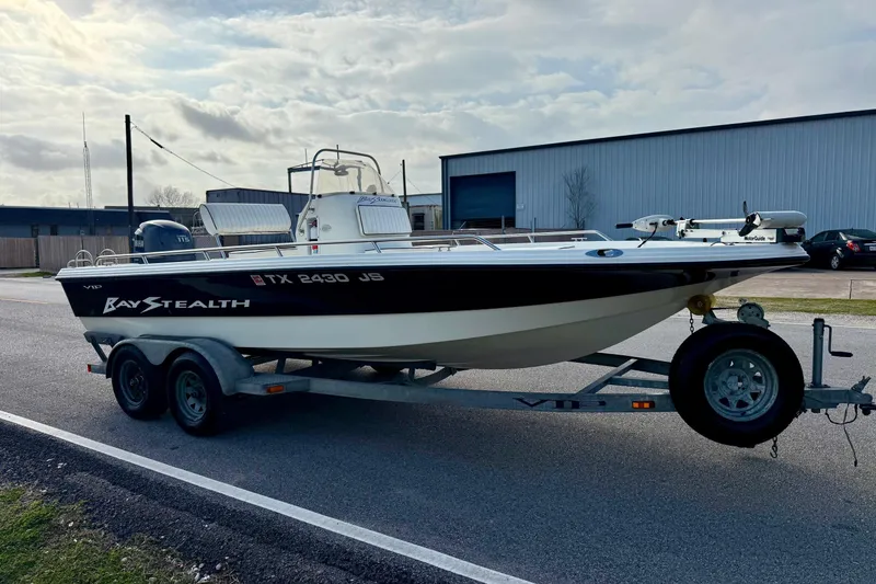 Slide: The Image of 2002 Bay Stealth 2030 boat on trailer, parked outdoors under cloudy sky. - 5