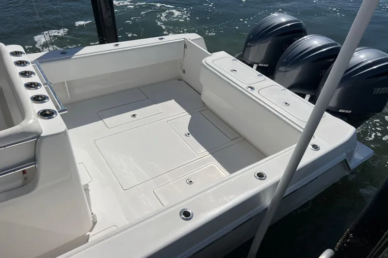 Slide: The Image of 2023 Contender 39 ST boat deck with triple outboard engines, docked on water. - 29