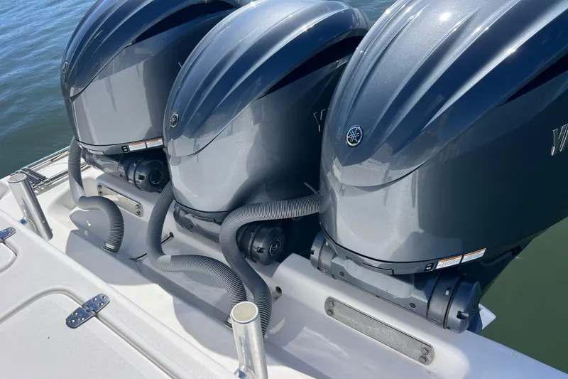 Slide: The Image of Triple outboard engines on a 2023 Contender 39 ST boat, docked on water. - 32