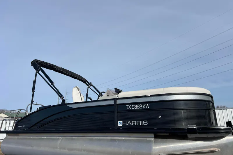 The Image of 2023 Harris Cruiser 210 SL pontoon boat with sleek black design and canopy. - 0