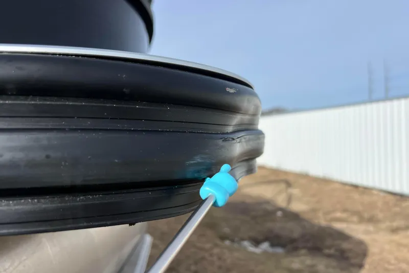 Slide: The Image of Close-up of a 2023 Harris Cruiser 210 SL boat's black rubber seal with a blue tool. - 11