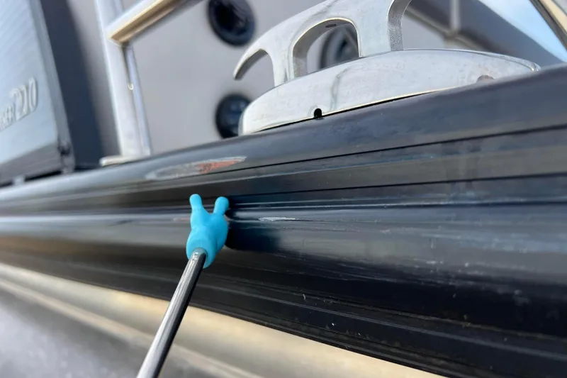 Slide: The Image of 2023 Harris Cruiser 210 SL boat detail with blue tool on black surface. - 14