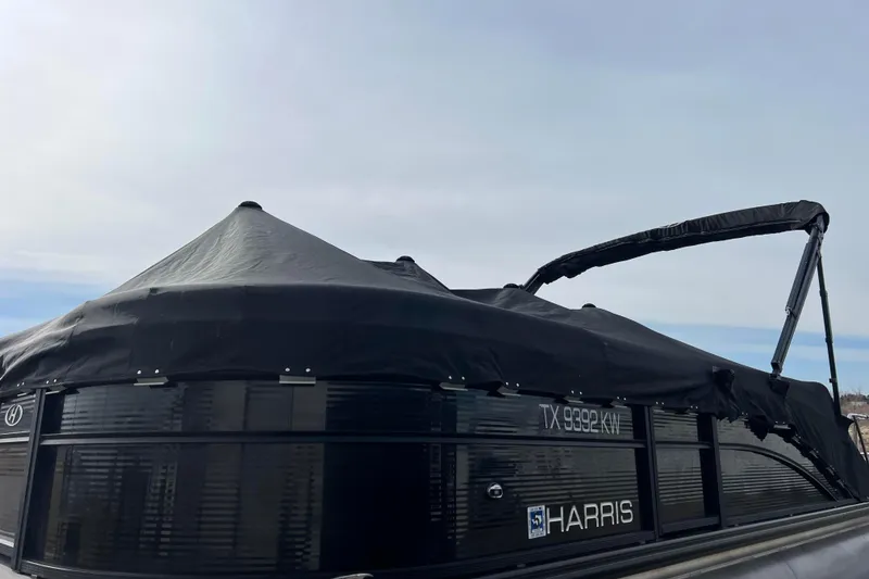 Slide: The Image of 2023 Harris Cruiser 210 SL boat with black cover, side view. - 50