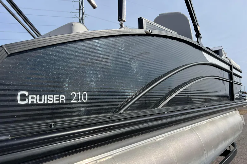 Slide: The Image of 2023 Harris Cruiser 210 SL pontoon boat, side view with sleek black design. - 6