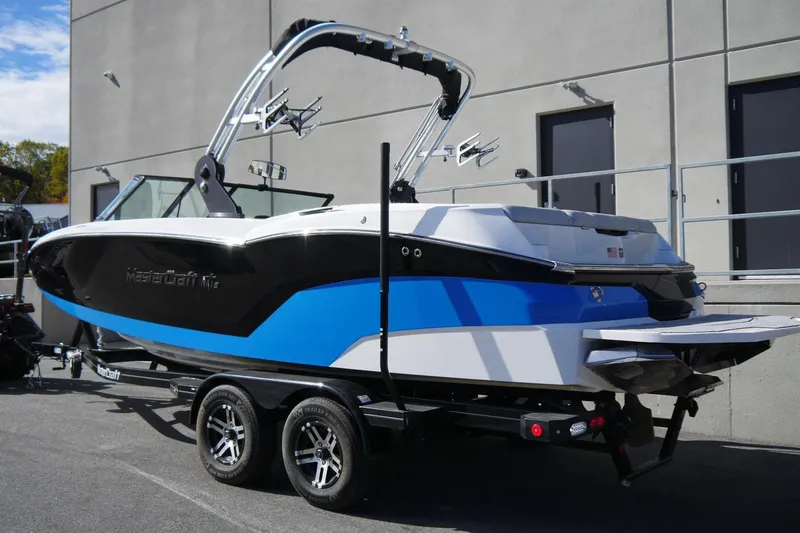 Slide: The Image of 2020 MasterCraft NXT22 boat on trailer, blue and black design, parked outdoors. - 5
