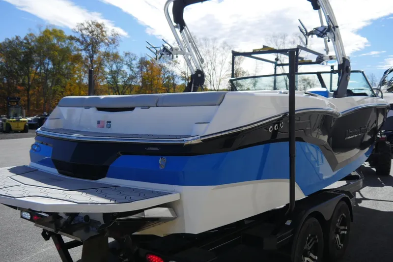 Slide: The Image of 2020 MasterCraft NXT22 boat with blue and white design on a trailer. - 7