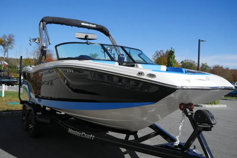 Slide: The Image of 2020 MasterCraft NXT22 boat on trailer, sleek design, blue and white accents, outdoor setting. - 8