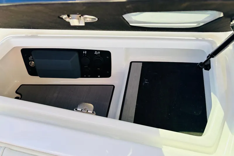 Slide: The Image of 2023 Nautique Super Air Nautique G25 storage compartment with control panel and latch. - 25