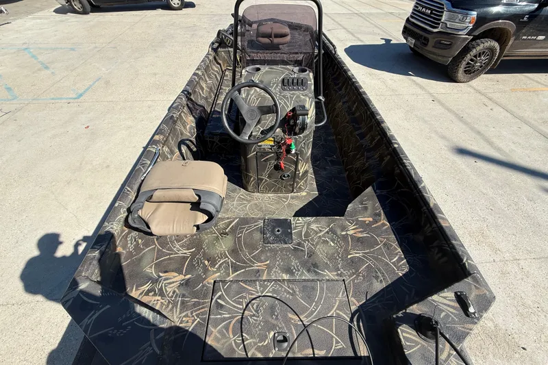 Slide: The Image of 2018 Excel F86 boat with camouflage interior, steering console, and seating, parked outdoors. - 7