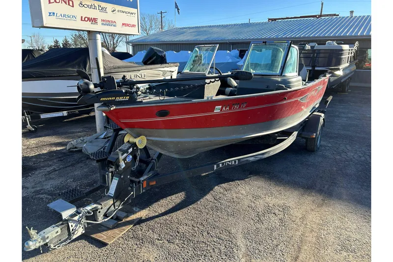 Slide: The Image of 2012 Lund 1775 Impact XS boat in red, parked on a trailer at a dealership. - 3