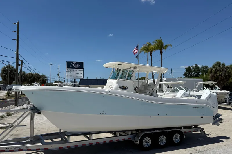 The Image of 2026 World Cat 325 CC boat on trailer, displayed outdoors under clear blue sky. - 2