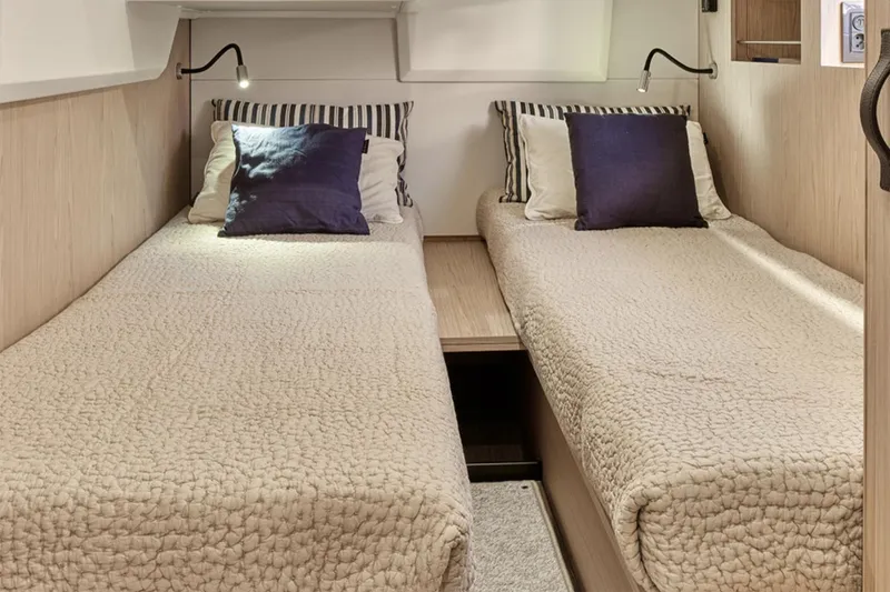 Slide: The Image of Manufacturer Provided Image: Twin beds in the 2026 Beneteau Swift Trawler 48 cabin, featuring cozy bedding and reading lights. - 8