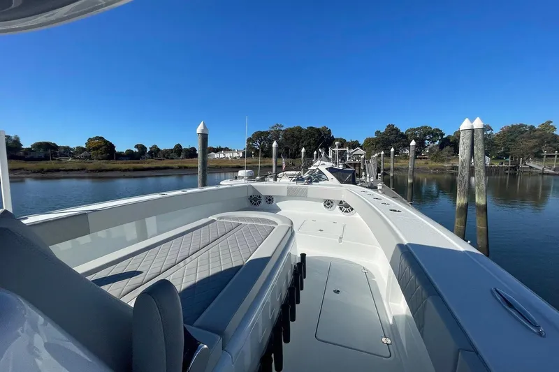 Slide: The Image of 2024 Freeman 42LR boat docked, showcasing spacious deck and seating under clear blue sky. - 8