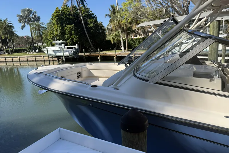 Slide: The Image of 2022 Grady-White Freedom 275 boat docked near waterfront home, palm trees in background. - 2