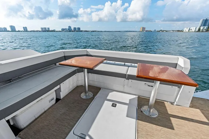 Slide: The Image of 2023 Cruisers 42 Cantius yacht deck with seating and tables, overlooking ocean and city skyline. - 20