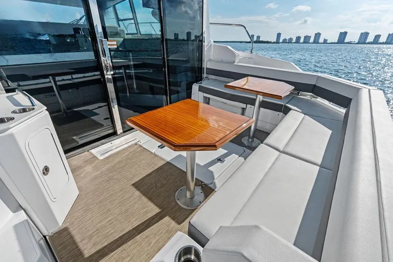 Slide: The Image of 2023 Cruisers 42 Cantius yacht deck with seating and tables, overlooking ocean skyline. - 22