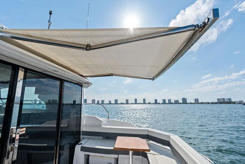 Slide: The Image of 2023 Cruisers 42 Cantius yacht with sunshade, overlooking a city skyline and water. - 23