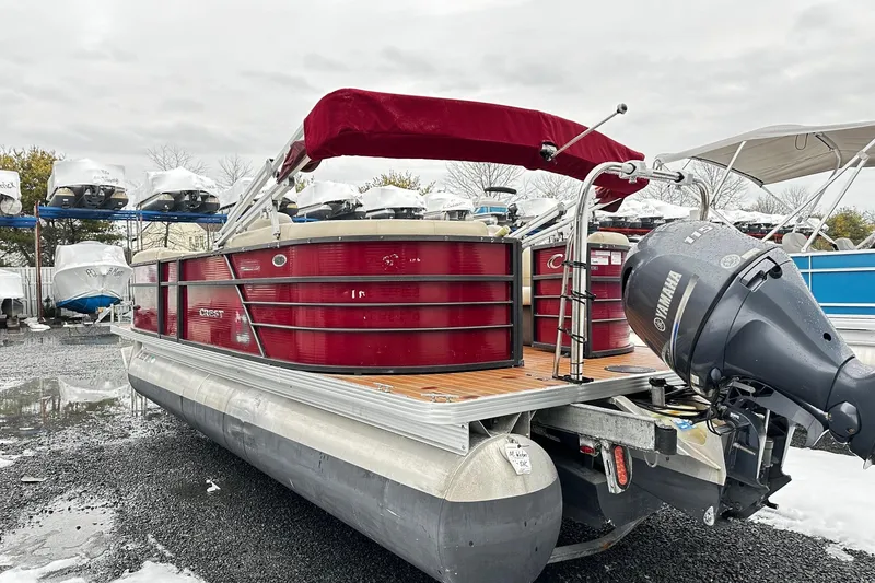 Slide: The Image of 2016 Crest Pontoon SLC OPT with Yamaha motor, red canopy, parked on wet ground. - 2