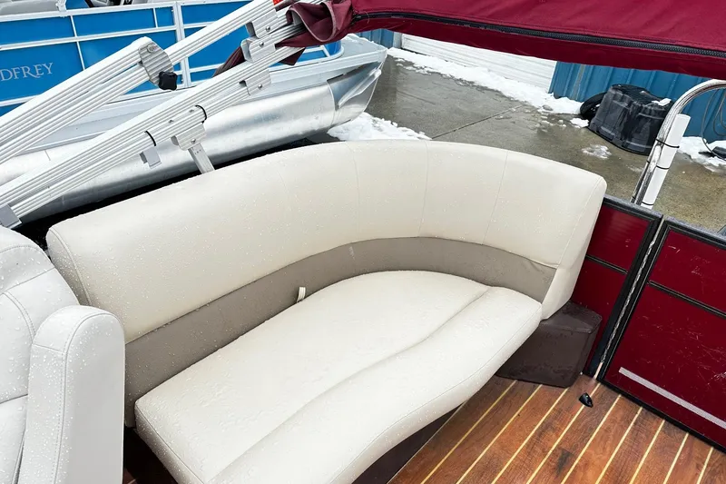 Slide: The Image of 2016 Crest Pontoon SLC OPT with beige seating and maroon canopy, wet from rain. - 9