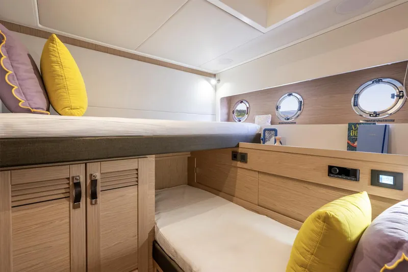 Slide: The Image of Manufacturer Provided Image: 2026 Beneteau Swift Trawler 54 cabin with bunk beds and portholes, featuring modern design. - 10