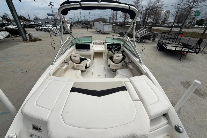 Slide: The Image of 2011 Chaparral 216 SSi Wide Tech boat interior with seating and steering wheel, docked outdoors. - 8