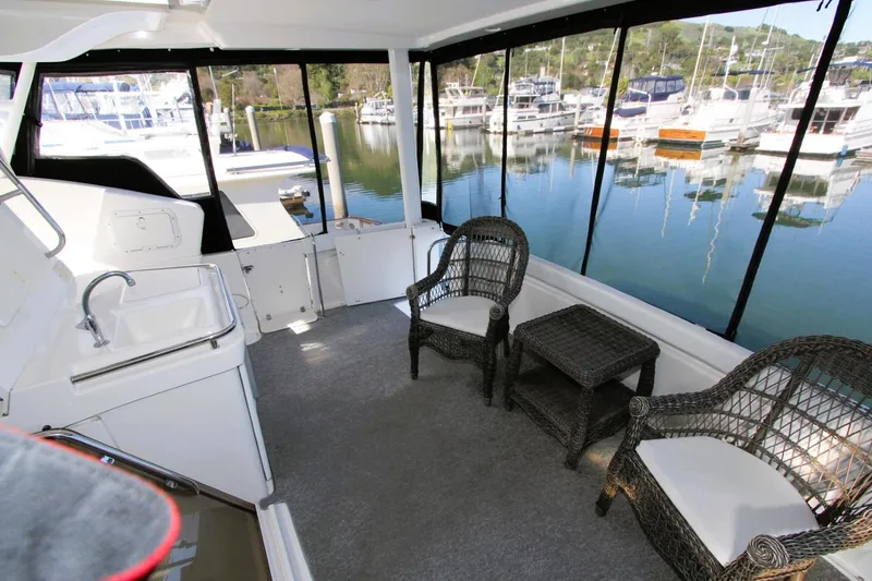 Slide: The Image of 1998 Silverton 372 Motor Yacht interior with wicker chairs, table, and marina view. - 24