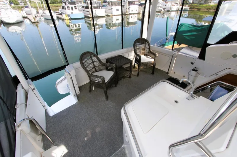 Slide: The Image of 1998 Silverton 372 Motor Yacht interior with wicker chairs and marina view. - 25