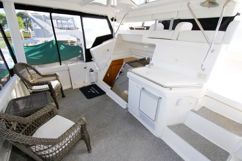 Slide: The Image of 1998 Silverton 372 Motor Yacht interior with wicker chairs and kitchenette. - 26