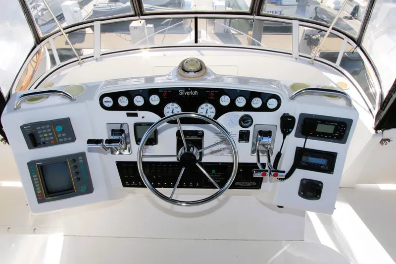 Slide: The Image of 1998 Silverton 372 Motor Yacht helm with steering wheel, gauges, and navigation controls. - 28