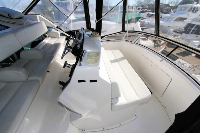 Slide: The Image of 1998 Silverton 372 Motor Yacht helm with white seating and steering wheel, docked at marina. - 30