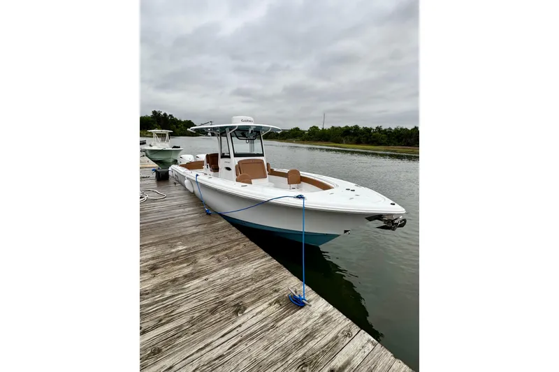 Slide: The Image of 2025 Sea Hunt Ultra 305 SE boat docked on a calm waterway. - 6