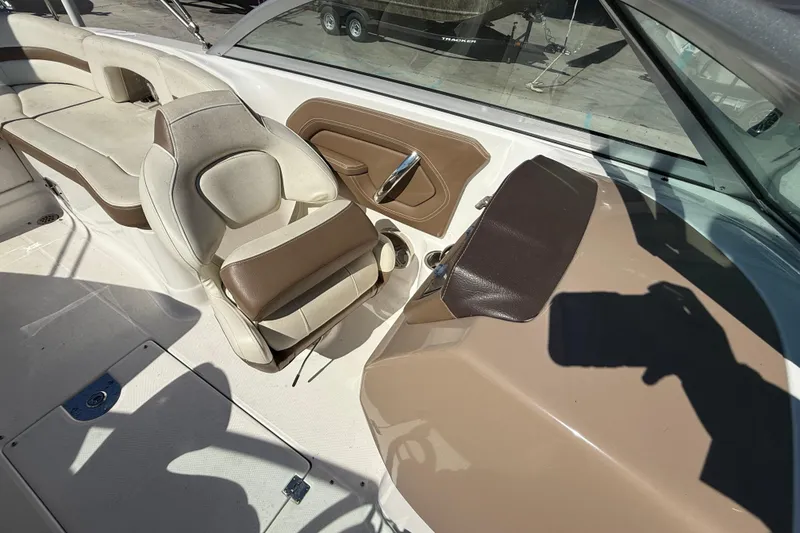 Slide: The Image of 2014 Chaparral 264 Sunesta boat interior with beige and brown seating and steering area. - 11