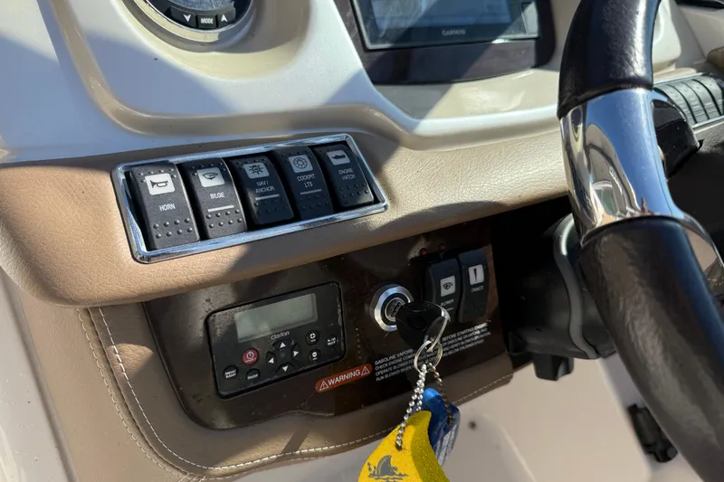 Slide: The Image of 2014 Chaparral 264 Sunesta dashboard with controls, steering wheel, and ignition keys. - 16