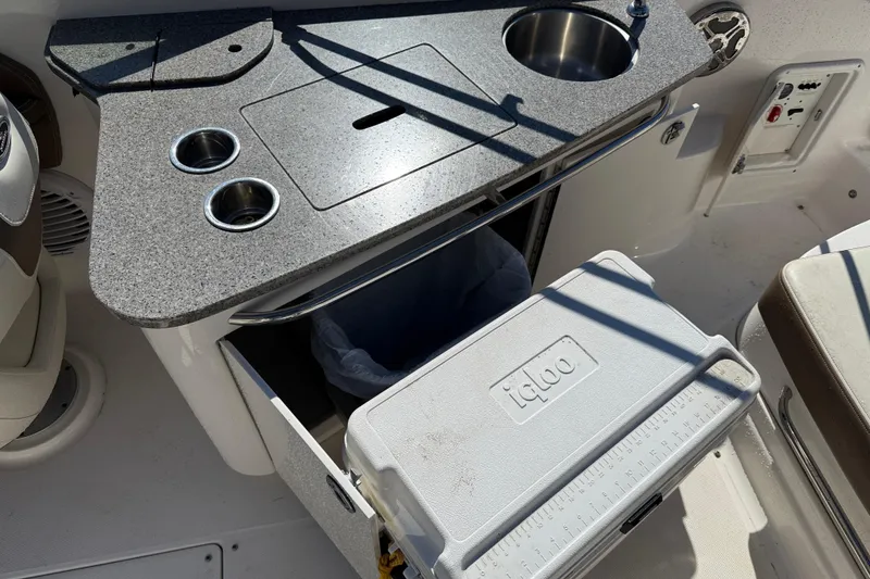 Slide: The Image of 2014 Chaparral 264 Sunesta boat kitchenette with sink, countertop, and Igloo cooler. - 19